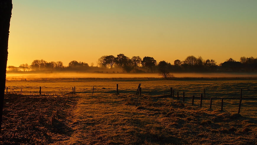 Golden sunrise over misty rural landscape with frost