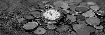 Vintage pocket watch on coins and sand in black and white