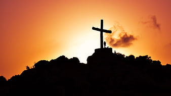 Silhouette of Cross on Mountain Peak at Sunset