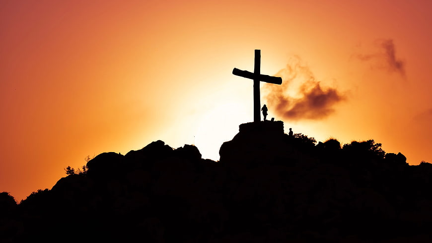 Silhouette of Cross on Mountain Peak at Sunset