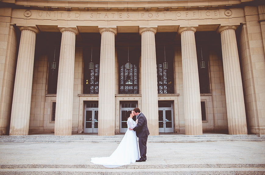 Bride and groom kissing in front of historic post office