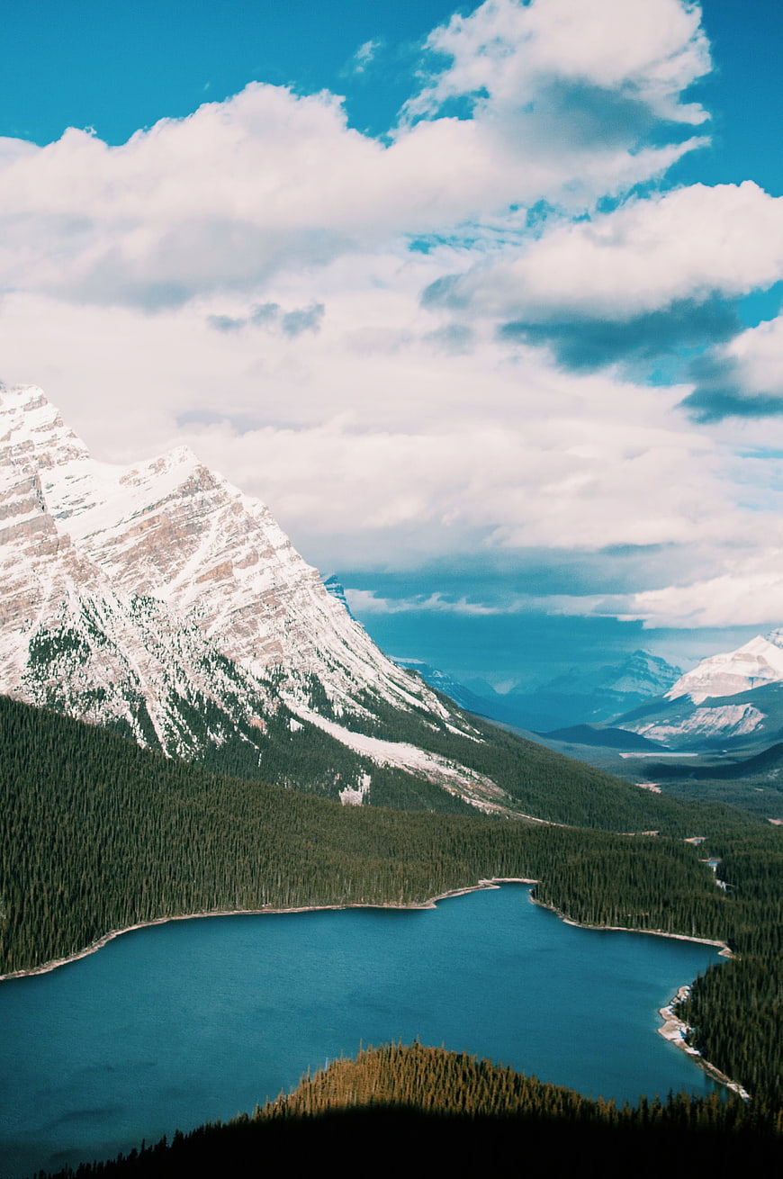 Snow-Capped Mountain Peak Overlooking Turquoise Lake and Forest