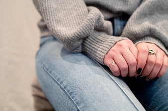 Close-up of woman's hands with rings and black manicure on jeans