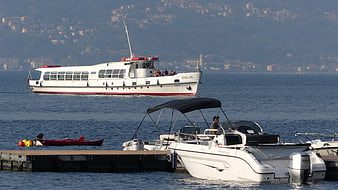 White ferry boat Giglio on Lake Como with docked motorboats