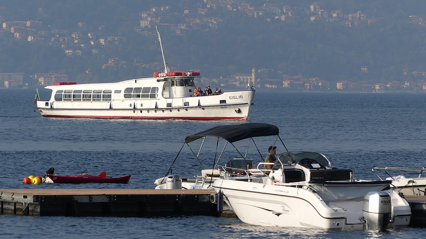 White ferry boat Giglio on Lake Como with docked motorboats