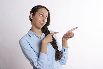 Young woman pointing right with confused expression on white background