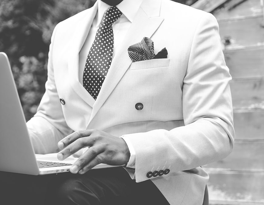 Businessman in white suit typing on laptop