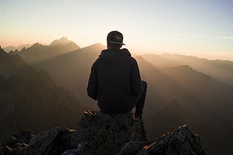 Man sitting on mountain peak watching sunrise