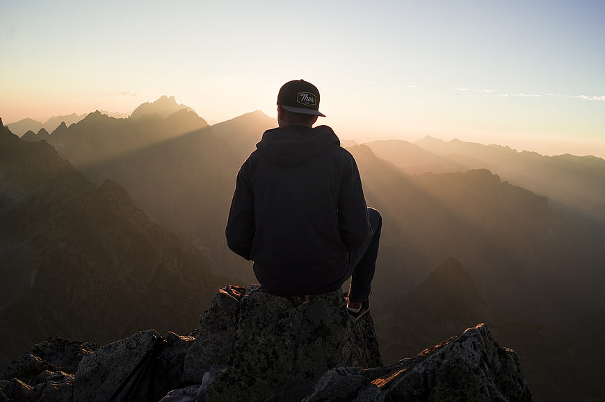 Man sitting on mountain peak watching sunrise