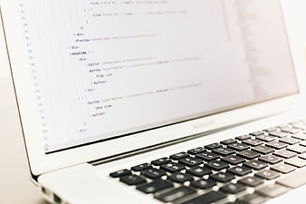 Close-up of MacBook Pro displaying HTML code on screen