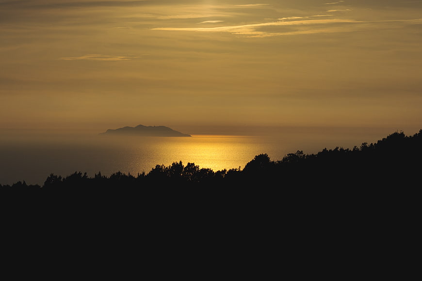 Golden Sunset Over Ocean With Distant Island Silhouette