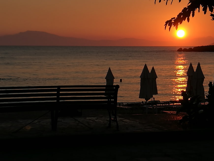 Silhouette of Beach Bench and Umbrellas at Sunset