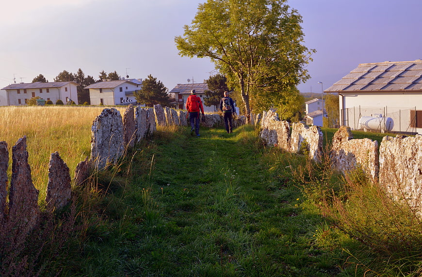 Hikers walking along ancient stone wall path in autumn