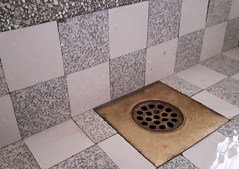 Close-up of vintage copper drain in tiled shower floor
