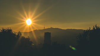 Golden sunrise over city skyline with sunburst and silhouettes