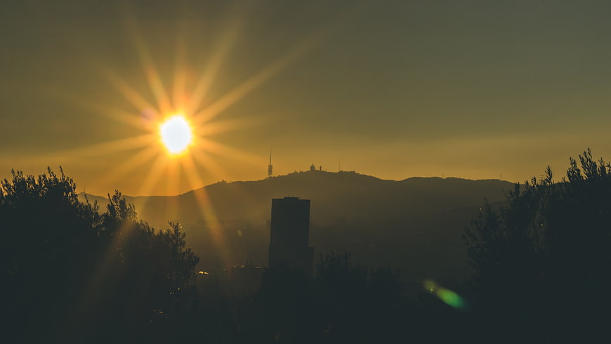 Golden sunrise over city skyline with sunburst and silhouettes