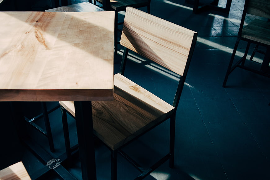 Modern wooden table and chair in sunlit cafe interior