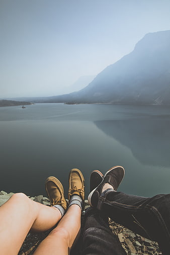 Couple's feet overlooking misty mountain lake view