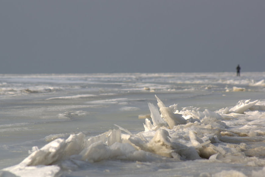 Man walking on frozen ice landscape with jagged ice formations