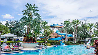 Family Relaxing at Resort Pool with Blue Water Slide