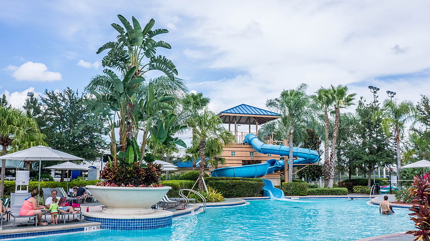 Family Relaxing at Resort Pool with Blue Water Slide