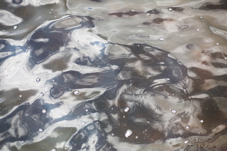 Abstract dark water surface with ripples and bubbles