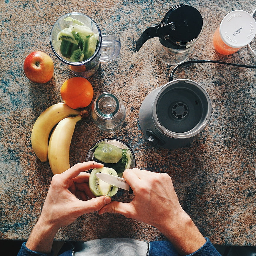 Top view of hands slicing kiwi for healthy smoothie preparation
