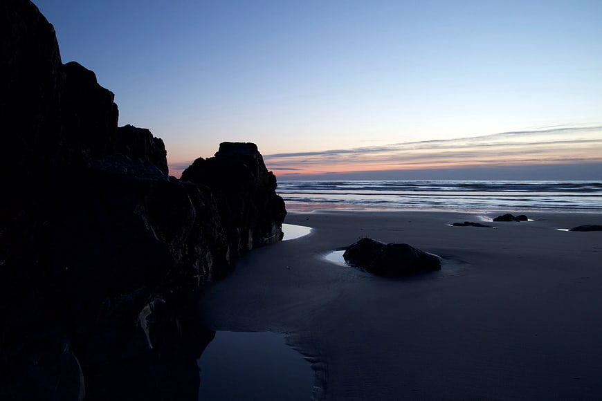 Silhouette of Black Rocks on Sandy Beach at Dusk