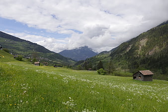 Alpine Meadow with Wooden Cabins and Mountain Valley