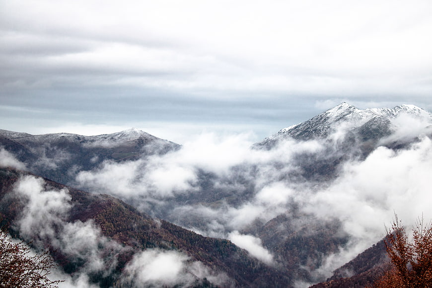 Snow-capped mountain peaks rising above thick clouds and fog