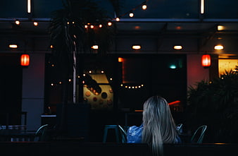 Woman Sitting Alone at Night with String Lights