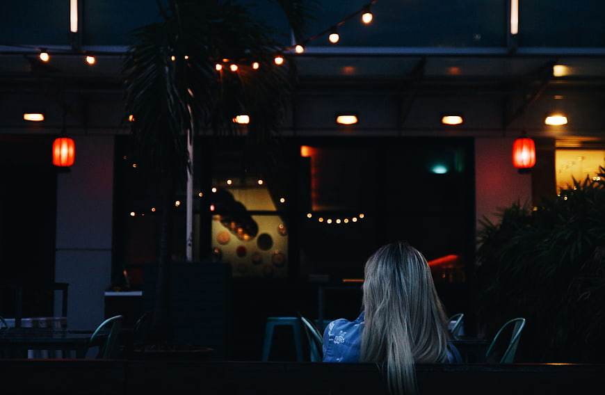 Woman Sitting Alone at Night with String Lights