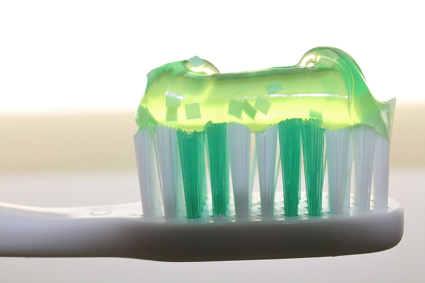 Close-up of green gel toothpaste on white toothbrush bristles
