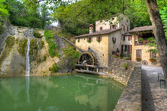 Historic stone watermill with wooden wheel and waterfall