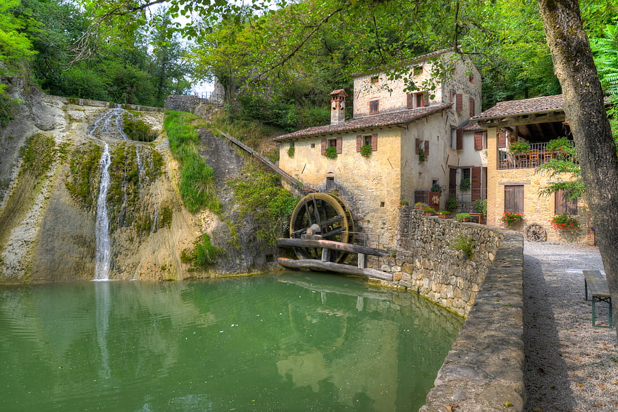 Historic stone watermill with wooden wheel and waterfall