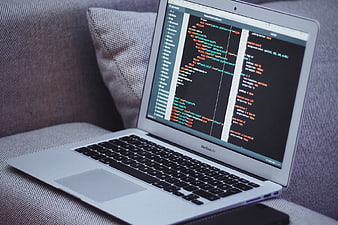 MacBook Air displaying code on a gray sofa