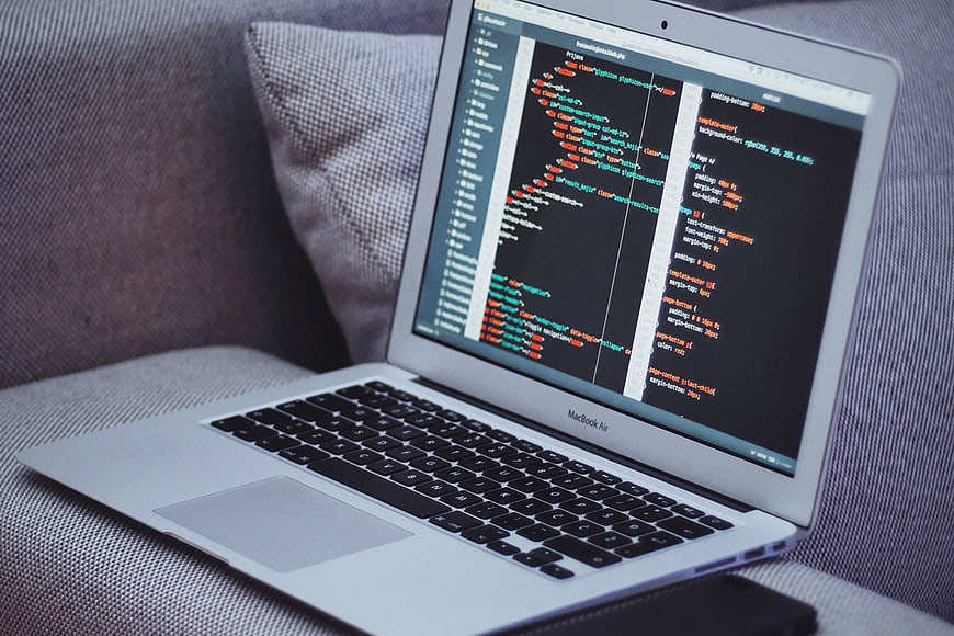 MacBook Air displaying code on a gray sofa