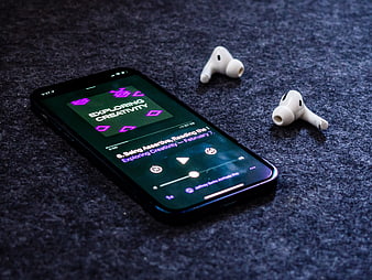 Smartphone Playing Podcast with Wireless Earbuds on Dark Surface