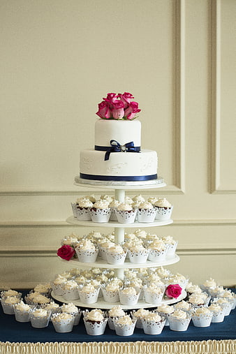 Elegant white wedding cake with cupcakes and pink roses