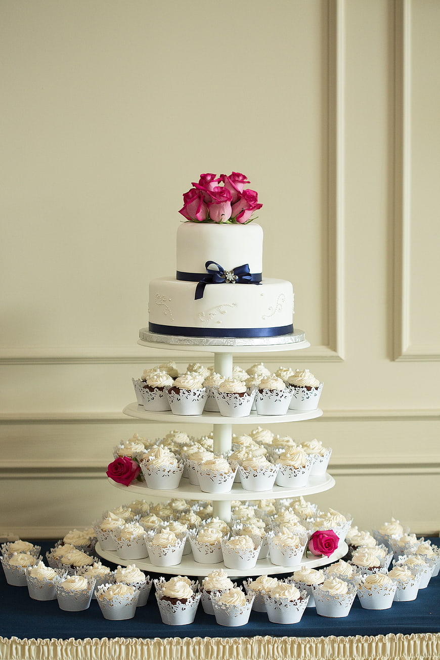 Elegant white wedding cake with cupcakes and pink roses