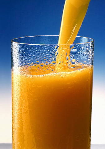 Fresh Orange Juice Pouring into a Condensation-Covered Glass