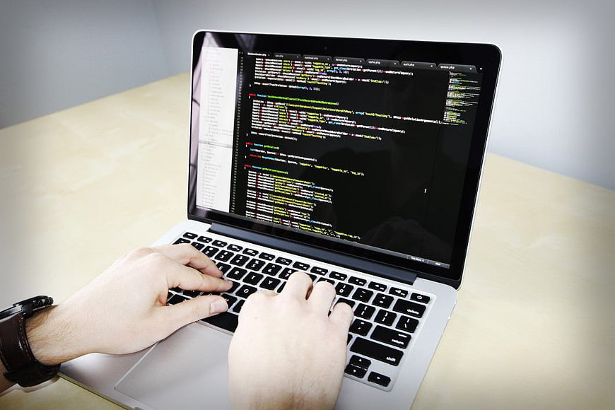 Hands typing code on a laptop computer screen