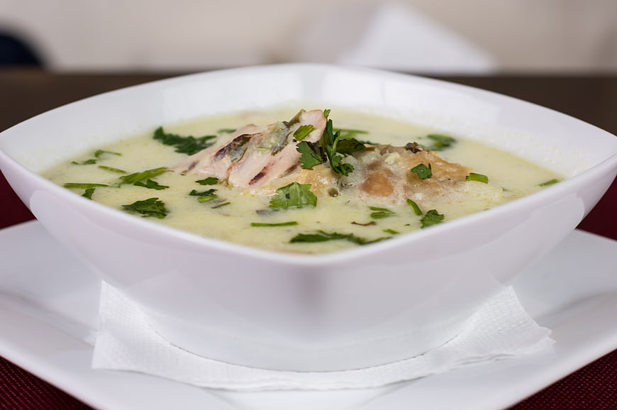 Creamy chicken soup with herbs in white bowl