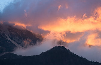 Dramatic sunset clouds over misty mountain peaks