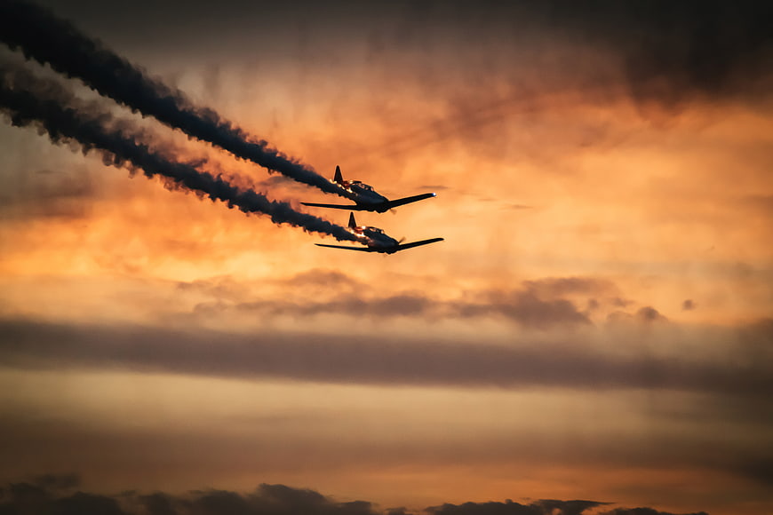 Two Aerobatic Planes Flying in Formation at Sunset