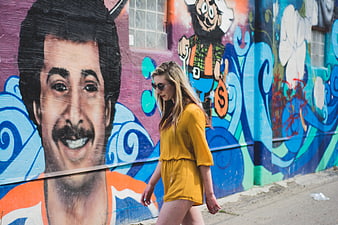 Woman in Yellow Dress Walking Past Colorful Graffiti Mural