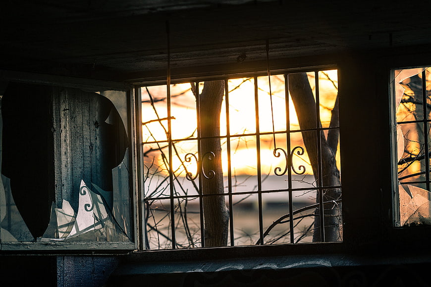 Sunset Through Broken Window Bars in Abandoned Building
