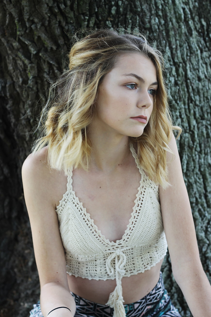 Young Woman in Crochet Top Leaning Against Tree