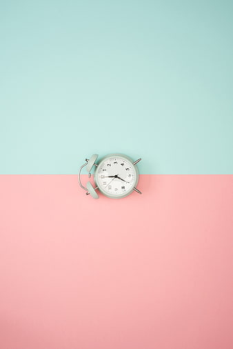 Minimalist alarm clock on pastel pink and blue background