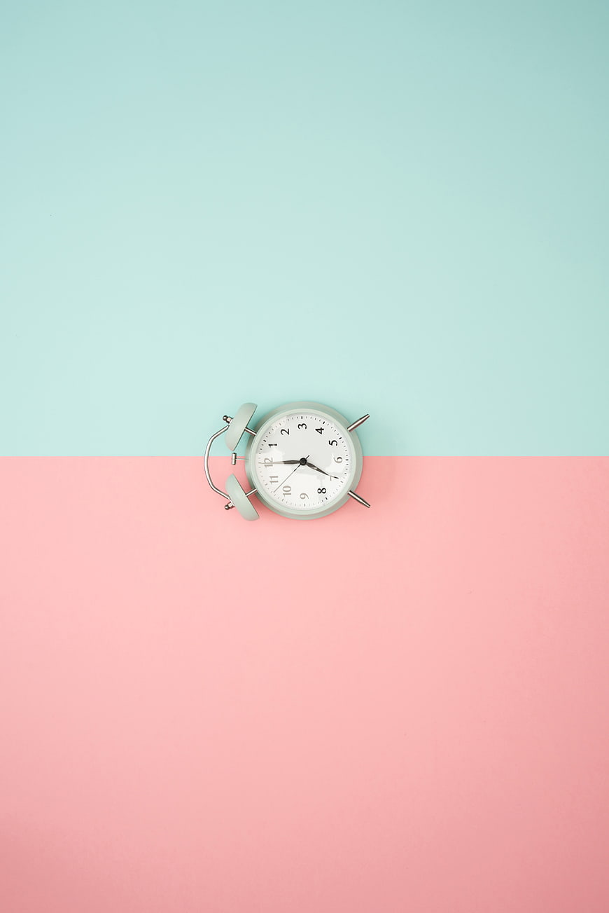 Minimalist alarm clock on pastel pink and blue background